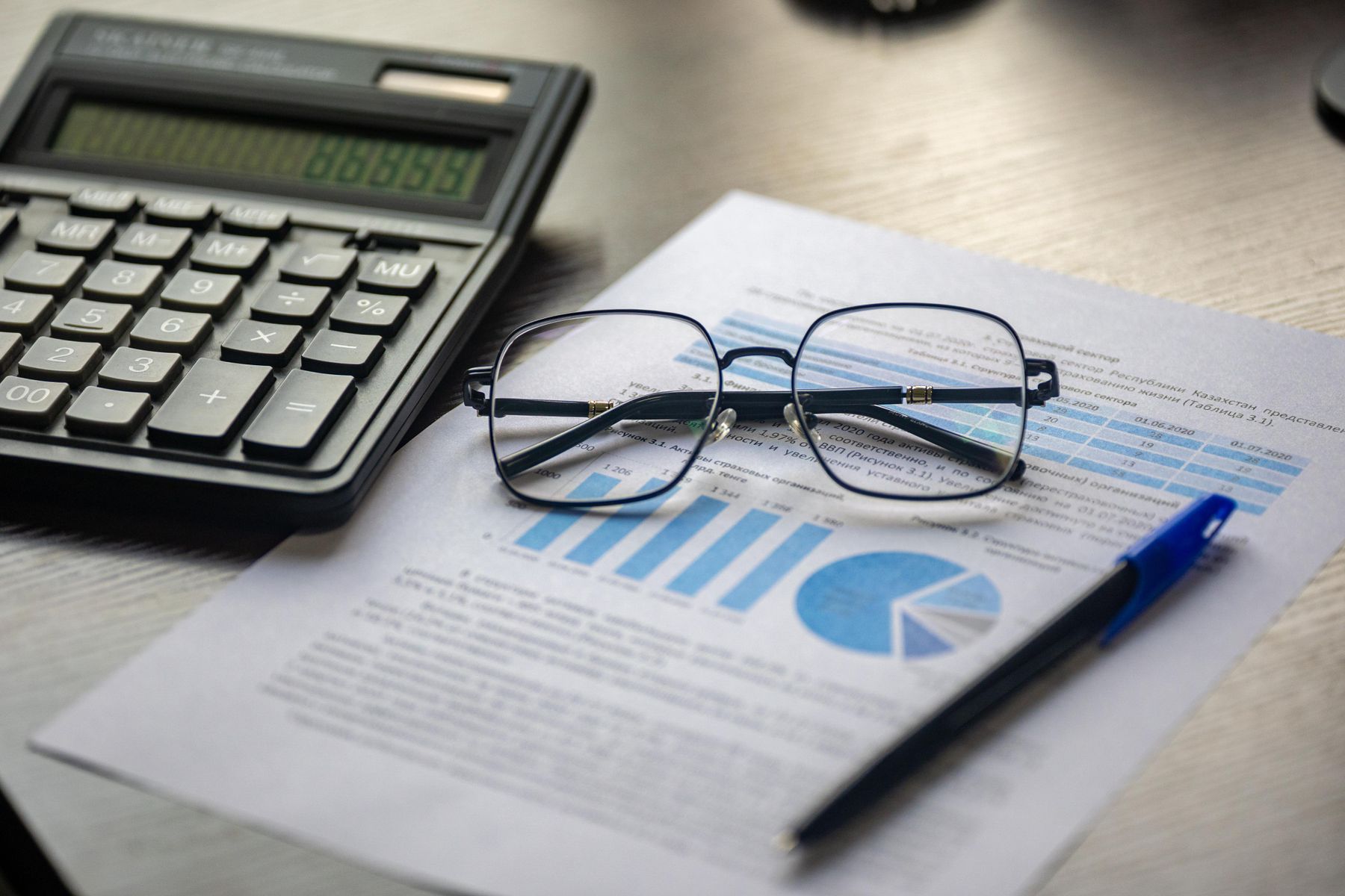 Financial report with a calculator, pen and reading glasses on a desk